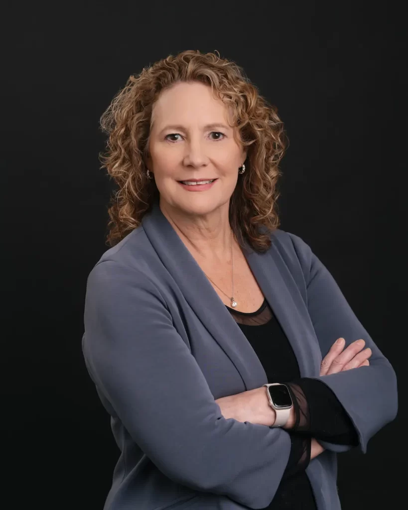 Headshot of Natalie Travers Smyre, General Manager & Broker, smiling with arms crossed.
